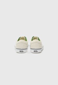 Beige suède sneakers met groene accenten bij de hiel, met een witte rubberen zool en het merklogo op de hiel. Laag bovenwerk.