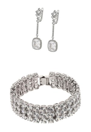 Srebrna bransoletka z wieloma przezroczystymi, okrągłymi kamieniami szlifowanymi na okrągło. Dwa pasujące srebrne kolczyki mają kwadratowy kamień i liniowy wzór.