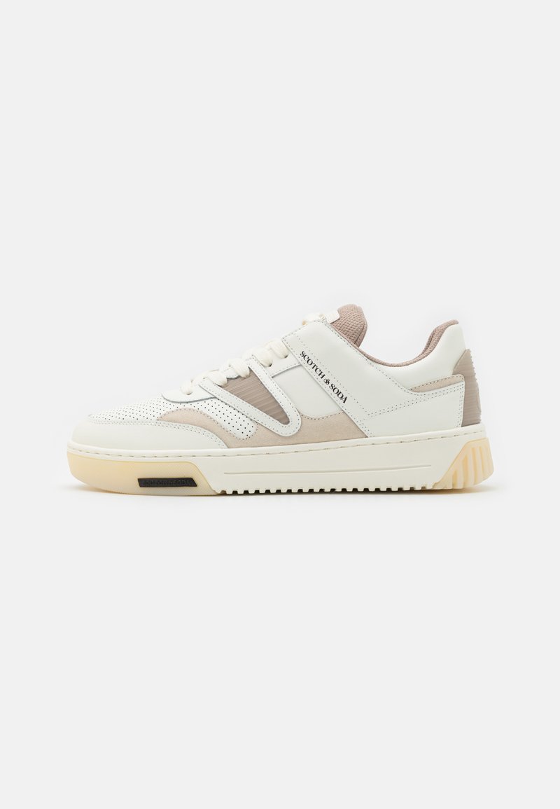 Witte en beige sneaker met een gemengde materiaalontwerp, perforatieaccenten, een dikke zool en een logo op de zijkant.