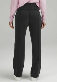 Svarta träningsbyxor med rak passform, elastisk midja och kontrasterande sömdetaljer. Mjuk tygkvalitet och något texturerad yta.