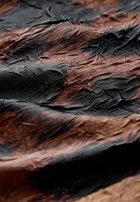 Tkanina o textured, z gradientem od głębokiej czerni do bogatego brązu, z widocznymi zmarszczkami i fałdami w całej powierzchni.