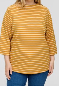 Mosterdgele top met witte horizontale strepen, ronde halslijn en driekwart mouwen. Zachte stof met een ontspannen pasvorm.