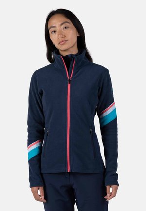 Marineblauer Fleece-Jacke mit hohem Kragen, rosa Reißverschluss und blau-weiß gestreiften Akzenten an den Ärmeln. Verfügt über Reißverschlusstaschen an den Seiten.