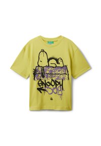 Žluté tričko s grafikou Snoopyho ležícího na fialovém graffiti stylu psí boudy a textem "Snoopy Dog" černými a fialovými písmeny.