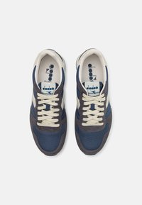 Blaue und graue Sneakers mit einem Obermaterial aus Mesh und Wildleder, cremefarbenen Schnürsenkeln und seitlichen Streifen. Im Inneren befindet sich das diadora-Logo.