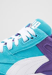 Suede sneakers with turquoise upper, white laces, and purple accents. Features a white logo and textured overlays for added detail.
