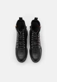 Bottines à lacets noires en simili cuir crocodile avec une finition texturée et des accents en métal doré. Comprend un col rembourré pour le confort.