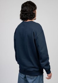 Navyblauwe sweatshirt met een ontspannen pasvorm, ronde hals en ribgebreide manchetten en onderkant. Gemaakt van een zachte, textuurstof, met een effen ontwerp.