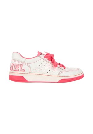 Baskets basses blanches avec accents roses, lacets roses, côté perforé et grand texte rose "CHANEL" sur le talon.