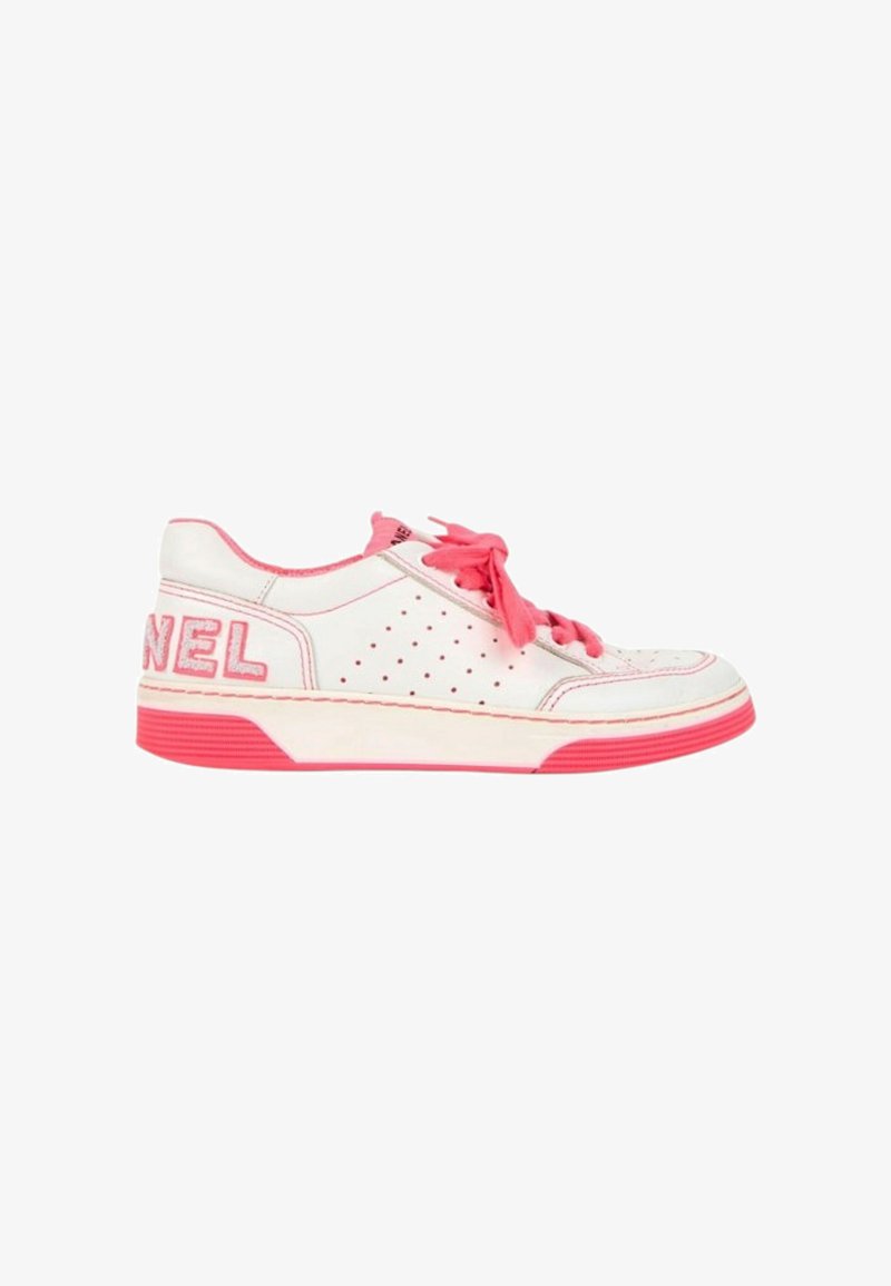 Baskets basses blanches avec accents roses, lacets roses, côté perforé et grand texte rose "CHANEL" sur le talon.