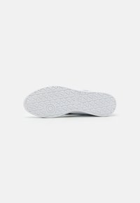 White sneaker sole featuring a textured pattern for grip, rounded heel, and a smooth surface with minimal branding.