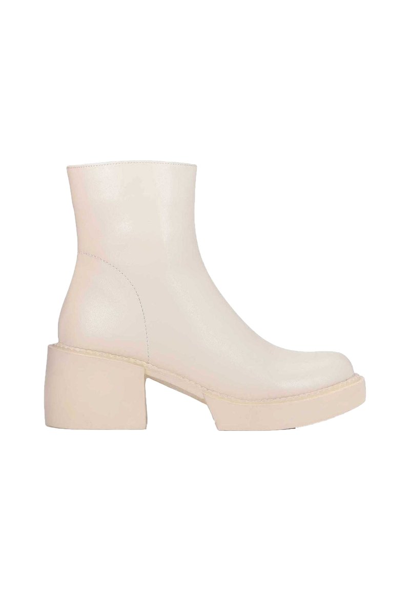 Bottines en cuir blanc avec un talon chunky, texture lisse, bout rond et détails de couture minimalistes. Conçues pour une silhouette moderne.