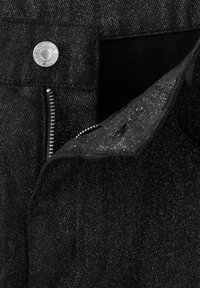 Jeans de mezclilla negra con cremallera, botón de metal plateado y textura sutilmente brillante. Bolsillo interior visible, destacando los detalles de diseño.