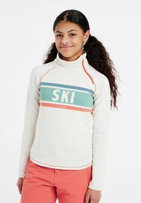 Maglione a collo alto di colore crema con strisce teal e corallo, caratterizzato dalla parola "SKI" in grassetto bianco. Tessuto morbido, design aderente e maniche lunghe.