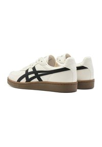Hvide lædersneakers med sorte detaljer og en struktureret overflade, samt en brun gummisål og rund tådesign.