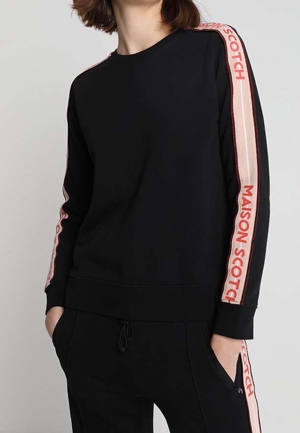 Czarna bluza z miękkiego materiału, z długimi rękawami w różowe i czerwone paski oraz napisem "MAISON SCOTCH" po bokach.