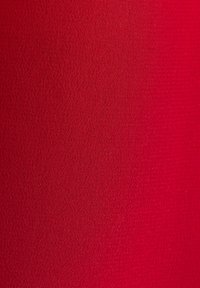 Gros plan sur un tissu rouge montrant une texture tissée fine et un motif tricoté serré avec des lignes horizontales subtiles.