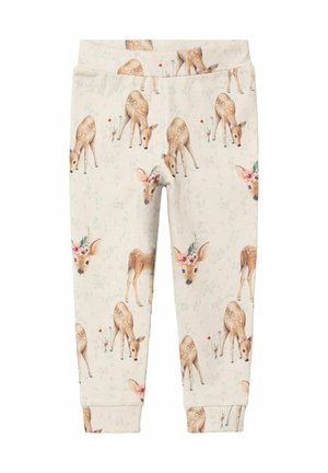 Pantalons de survêtement beiges avec un motif de cerf, offrant une texture douce, une taille élastique et des poignets côtelés. Le design inclut des accents floraux autour du cerf.