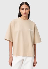 Beżowy, oversize t-shirt wykonany z miękkiego materiału, z okrągłym dekoltem i krótkimi rękawami. Małe logo "ALLSAINTS" w kolorze białym na piersi.