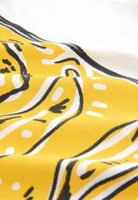 Tissu jaune avec un motif abstrait audacieux en noir et blanc, présentant une texture lisse et des couleurs vibrantes, créant un contraste visuel.