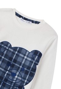 Biała bluza z miękkiego materiału, ozdobiona pluszowym wzorem granatowego misia w kratkę. Miękka tekstura i okrągły dekolt, odpowiednia dla dzieci.