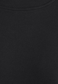 Tela de punto negra con una textura suave, que presenta un cuello acanalado y un color uniforme, mostrando costuras uniformes en toda la prenda.