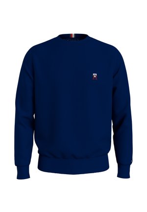 Gładka granatowa bluza z okrągłym dekoltem i małym białym oraz czerwonym logo „T” po lewej stronie klatki piersiowej; brak widocznego modela czy szczegółów tła.