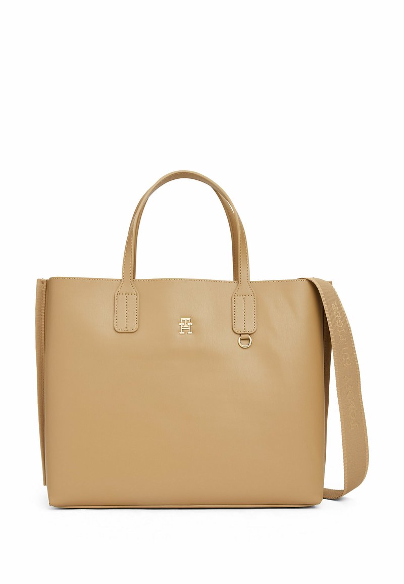 Borsa a tracolla in pelle tan con due manici e una tracolla rimovibile. Presenta un logo dorato e una texture liscia, con elementi di design minimalisti.