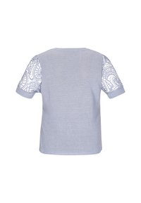 Lys blå kortærmet bluse med tekstureret hovedstof og detaljerede blondeærmer, der har et blomster mønster. Enkel design med rund hals.