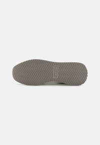 Calvin Klein joggesko-såle, med teksturert grå gummi med zigzag-mønster og merket panel. Jevne kanter og flat design.