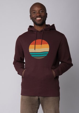 Bordeauxkleurige hoodie met een cirkelvormige grafiek die gelaagde kleuren bevat: rode, oranje, beige en blauwe strepen. Casual ontwerp met zijzakken.