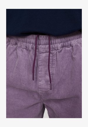 Paarse corduroy broek met verticale geribbelde textuur en een elastische tailleband. Voorzien van een paarse trekkoord met puntige uiteinden voor aanpassing.