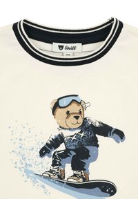 Biała koszulka z czarnobiałą prążkowaną kołnierzykiem, z grafiką niedźwiedzia snowboardowego, ubranego w sweter, rękawice i gogle.