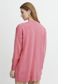 Maglione a maniche lunghe in tessuto rosa testurizzato, con vestibilità comoda, polsini e orlo a costine, scollatura rotonda e dettagli minimi.