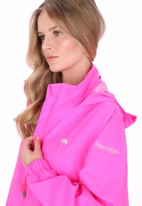 Rózsaszín vízálló kabát magas gallérral, állítható húzózsinórral, elasztikus mandzsettákkal és egy kis esernyő logóval a mellkason.