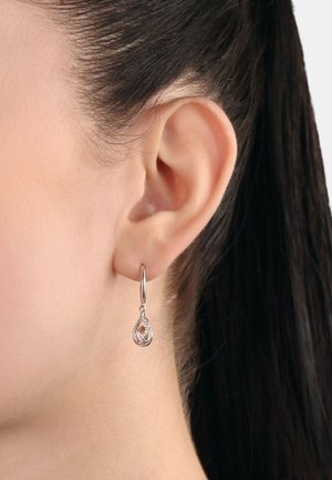 Silberne Tropfenohrringe mit einem roségoldenen Akzent und aufwendigem Durchbruchsdesign. Die Ohrringe hängen an einem kleinen Ring.