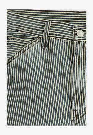 Tissu en denim rayé bleu et crème présentant un bouton, des surpiqûres et des passants de ceinture ; texture lisse avec une forme structurée.