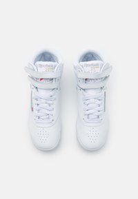 Białe trampki w stylu wysokich sneakersów z perforowanym noskiem, sznurówkami i rzepem. Wykonane z materiału skórzanego z logo "Reebok Classic" na języku.
