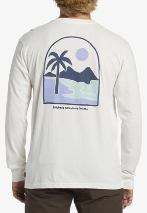 Camisa de manga larga en color crema que presenta un gráfico de una palmera, montañas y un sol en tonos azules y verdes, con el texto "Billabong Adventure Division".
