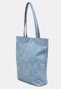Sac fourre-tout en denim bleu avec des anses longues et étroites, forme rectangulaire, texture lisse et un détail central de couture.