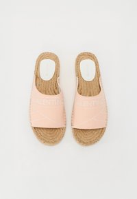 Pantofole slip-on rosa in tela con suola in juta. Presentano un logo cucito e linee bianche diagonali sulla superficie superiore.