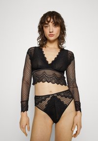 Sorte blonde lingerie-set med lange ermer, bølgete kanter og geometriske mønstre. Har en kort topp og matchende høyt liv truser.