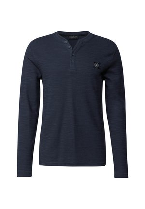 Marineblaues Langarmhemd aus strukturiertem Stoff, mit einem knöpfbaren Kragen und einem kleinen Logo-Patch auf der oberen linken Seite.