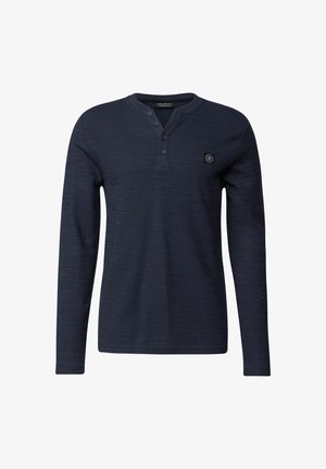 Camicia a maniche lunghe blu navy in un tessuto strutturato, con colletto con bottoni e una piccola etichetta con logo sul lato superiore sinistro.