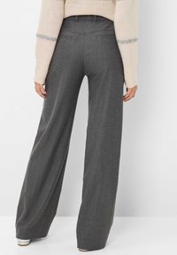 Hellgraue weite Hose aus strukturiertem Stoff, mit zwei Gesäßtaschen, hohem Bund und entspannter Passform. Kombiniert mit einem leichten Pullover.