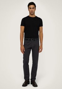 Czarna koszulka krótki rękaw zestawiona z szarymi spodniami i czarnym paskiem. Buty są ciemnobrązowe, o gładkim, wypolerowanym wykończeniu.