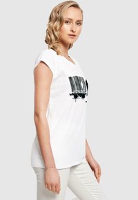 Hvid bomulds t-shirt med korte ærmer, prydet med et sort stregkodegrafik på forsiden. Glat tekstur; afslappet pasform; minimalistisk design.