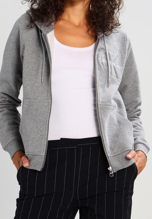 Gray zip-up hoodie with drawstrings, featuring a small logo on the chest, paired with black pinstriped pants. Soft fabric texture.