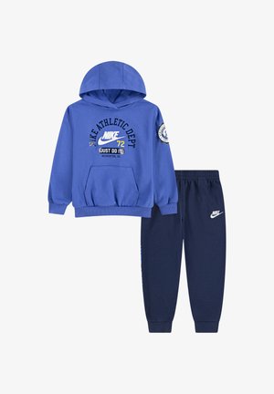 Sudadera de algodón azul con capucha, bolsillo delantero y texto gráfico; combinada con pantalones jogger azul marino que presentan un logo y cintura elástica.