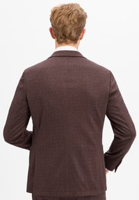 Brauner strukturierter Anzugjacke von hinten betrachtet, mit klassischem Kragen und einem Sch vent. Der Stoff hat ein gewebtes Muster.